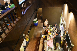 居酒屋の2階から、数人が作業をしている1階のカウンターを写した写真