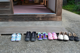 神社の拝殿前の入り口に、大人用と子ども用の靴がきれいに並べられている写真