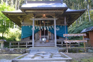 森の中にある伝統的な神社の社殿の正面外観の写真