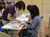 席に座った女性の受講者のテキストを指さし、指導をしている佐藤金枝先生の写真