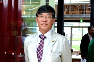 白いスーツを着用した鈴木さんを正面から写した写真