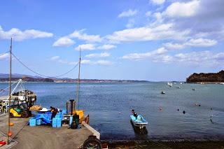 穏やかな水面に波ひとつ立たず、小さな舟が一隻だけ静かに浮かんでいる港の様子を写した写真