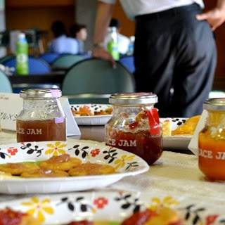 テーブルの上に花柄の紙皿に盛られたジャムを乗せたクラッカーと「RICE JAM」と書かれた数種類の瓶詰めのジャムが並べられている写真