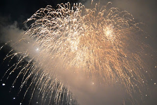 夜空に無数の金色の光が流れるように広がる、大玉の打ち上げ花火の様子を写した写真