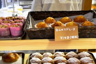 棚に並んだ焼き菓子がアップで写っており、「お山のマドレーヌ」と書かれた札の前にふっくらとしたマドレーヌがかごに盛られている焼き菓子の写真