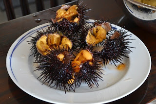 4個の大きなとげつきのウニの殻が割られて白いお皿に盛りつけされている写真
