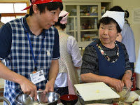 男性スタッフが調味料が入ったボウルを混ぜながら参加者の女性と話している様子の写真