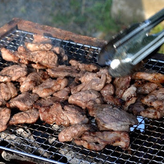 ラム肉をトングを使いながら網の上で焼いている様子をアップで写した写真