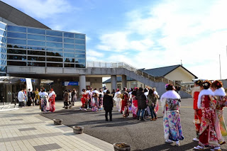 振袖やスーツを着た新成人たちが、会場の外に集まっている成人式会場前の屋外の写真