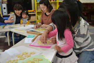 子どもたちと大人が一緒にテーブルを囲みながら、楽しそうにクッキーの型抜きに取り組んでいる様子の写真