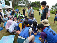 芝生の広場にたくさんの人が集まり、水風船の準備をしている写真