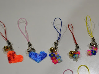 オレンジと青のハート、ちいさな色違いの花のモチーフなど、できあがった5つのアイロンビーズストラップの写真