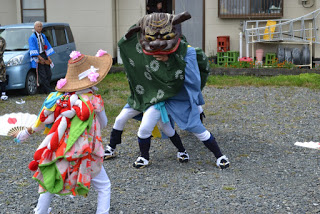 伝統的な獅子舞の衣装を身にまとった二人の子どもが向かい合って舞っている様子の写真