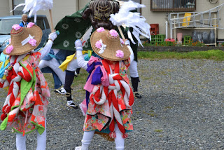扇子を持った二人の子どもと緑色の獅子舞衣装を着た大人が踊っている様子の写真