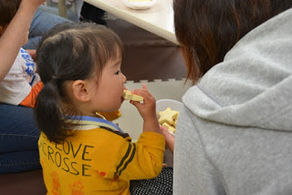黄色いシャツを着た小さい女の子が星形のクッキーを口にしている様子を右後方から写した写真