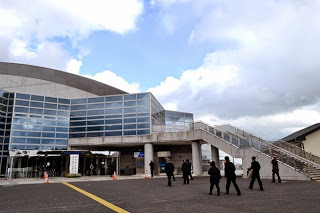 大きな窓が特徴でガラスとコンクリートで造られた現代的な建物のベイサイドアリーナの外観、右側には階段があり、人々が歩いている様子の写真