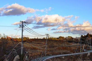 夕暮れの空の下、盛土がされた復興途中の寄木地区の土地に重機が見える復興の現状の写真
