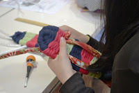 参加者がカラフルな布を使って作った布ぞうりの鼻緒部分を結びつける作業を手元で丁寧に行っている写真