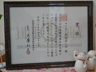 優秀賞を受賞した全国理容生活衛生同業組合連合会から贈られた賞状が額に入れられて飾られている写真