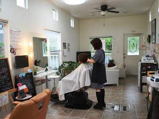 店内の椅子に座る客の髪をスタイリストが丁寧に整えている施術中の美容室の写真