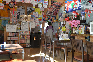 壁や天井にポスターや装飾がたくさん貼られ、カウンターとテーブル席がある温かみのある雰囲気の店内の写真