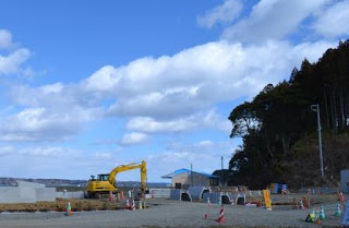 緑や赤のコーンが置かれた工事現場に黄色い大型の重機がある写真