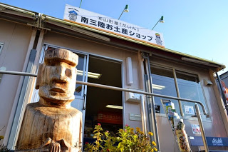 「南三陸お土産ショップ」の看板が掲げられた店舗の建物の前に、木彫りのモアイ像が置かれている写真