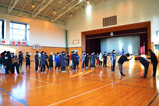 参加者の皆さんが体育館内で整列し、参加者の前に表彰者が立って表彰を行っている様子を写した写真