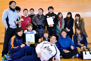 ットサルのメンバーらしき男女が座り込んだり立ったりして、表彰状やトロフィーを持ち笑顔でポーズをとっている集合写真