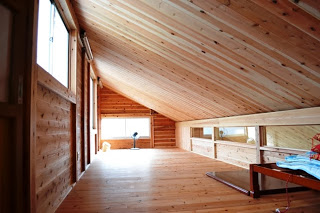 木製梁と板張りの屋根裏空間に、光が差し込み、広々とした斜め天井のロフト部分が写っている写真