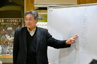 ホワイトボードに大きく「金色堂」と縦書きした文字の傍に左手を置き解説をする小野寺講師の写真