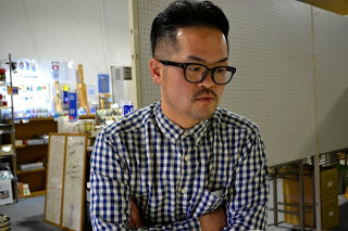 チェックのシャツに黒縁メガネの柳井さんが腕組をしている様子を写した写真