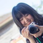 学生ライター 稲葉百々佳さんが笑顔で手に持ったカメラを見ている写真