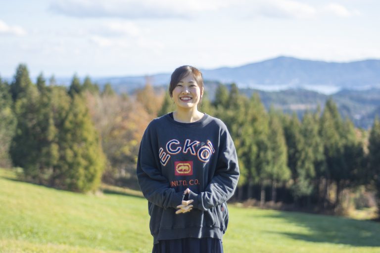 広い草原の中に立っている、スウェットシャツを着た大沼ほのかさんの写真
