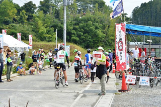 休憩所で自転車を降りた参加者たちが自転車を置いてテントのある場所に集まっている写真