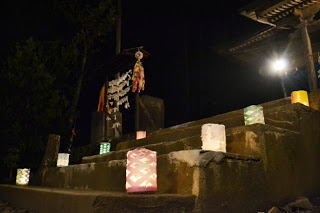 色とりどりの和紙の灯籠が石段に並べられ、夜の神社の境内がやさしい灯りで照らされている様子の写真
