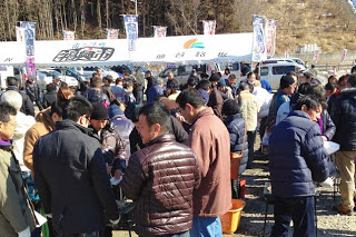 多くの来場者が出店のテント前に集まり、のぼり旗が並ぶにぎやかな会場の一角を写した写真