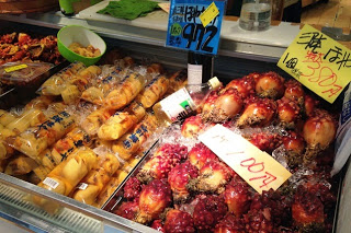 右側に赤いホヤ、左側に透明のビニール袋に入った商品が並び、上には手書きの値札が貼られた冷蔵ショーケースの商品陳列の写真