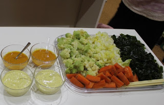 数種類の温野菜とワカメが盛り付けられた大きな四角い皿の横に、オレンジ色と薄い黄色の2種類のドレッシングが入った透明の小皿が4つ並んでいる写真