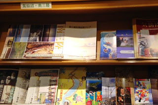 木の棚に「気仙沼・南三陸」と書かれた案内の下に、多彩な観光パンフレットがずらりと並べられている写真