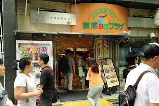 「宮城ふるさとプラザ」と書かれた看板のある入口から多くの人が出入りしている写真