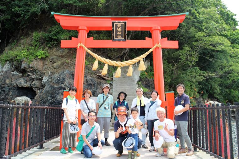 鳥居の前でヘルメットを持った大人と子ども十数人が笑顔で並んでいる集合写真