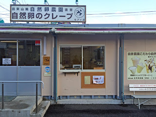 「自然卵のクレープ」と書かれた看板を屋根の上に掲げた店舗の外観写真