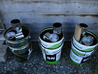 ペール缶の中に煙突部品や小さめの缶が入ったロケットストーブの材料が3つ並んで置かれている写真