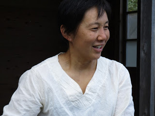 白いシャツを着た女性が屋外で笑顔を見せている写真