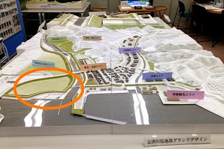 各エリアに色分けされたラベルが貼られた北釜地区の再開発プランの立体模型が机に置かれ、左下の松原地区がオレンジ色の円で記されている写真