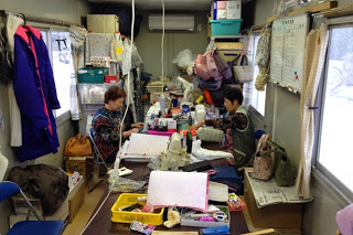 部屋の中で高齢の女性たちがミシンを使って裁縫作業をしている様子の写真