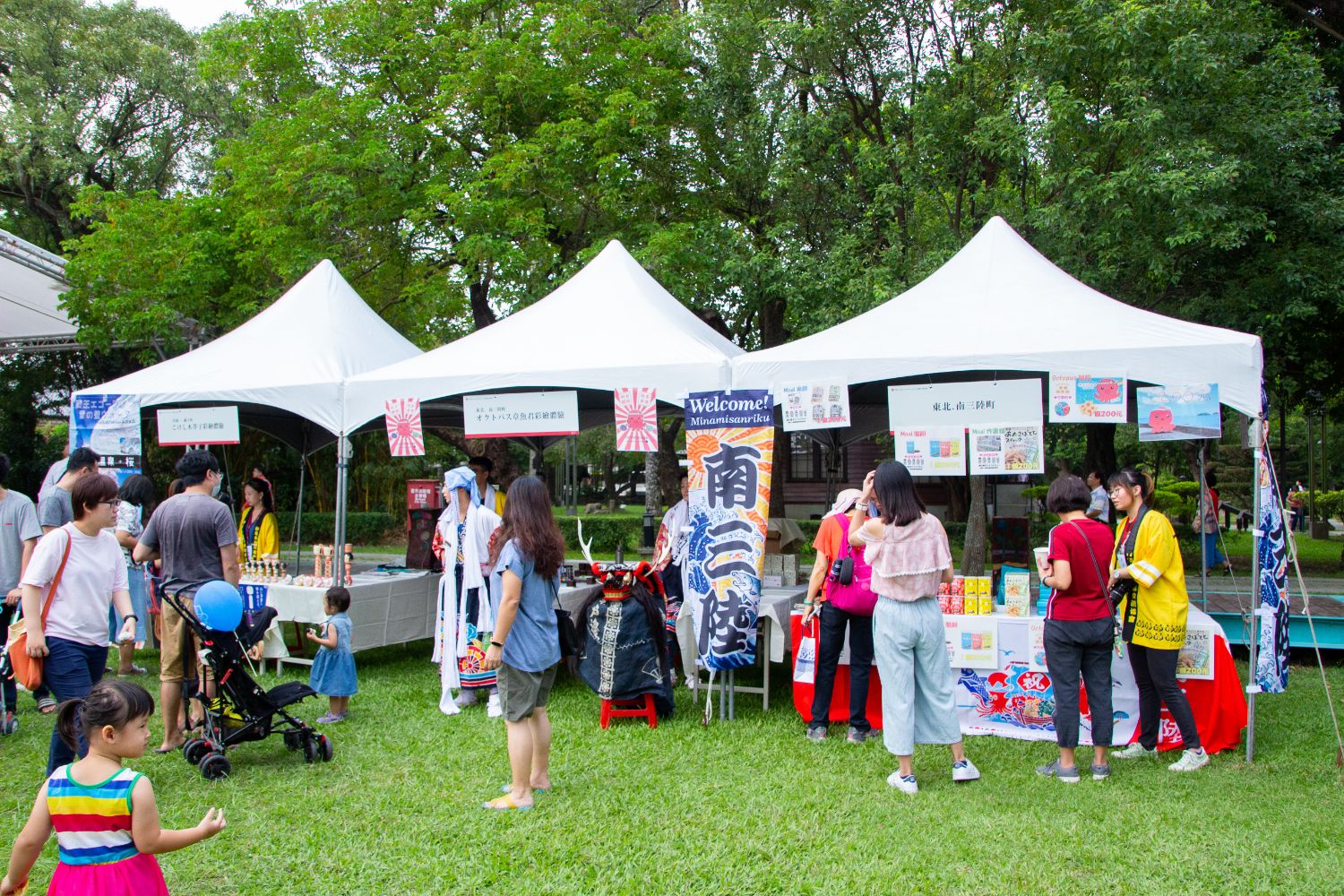 屋外の芝生の上に設置された白いテントのブースに、多くの人が集まっている和風文化祭の様子の写真