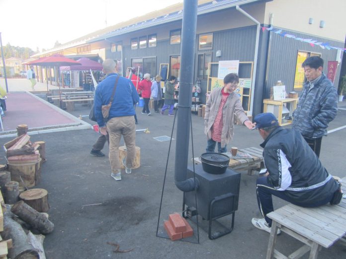 人々が屋外で集まり、薪ストーブの周りに座っている様子の写真