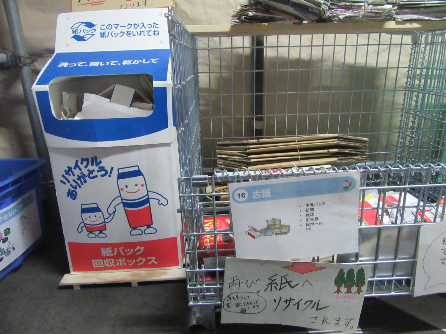 紙パック回収ボックスと古紙回収用の金属製のカゴが並んでいる写真